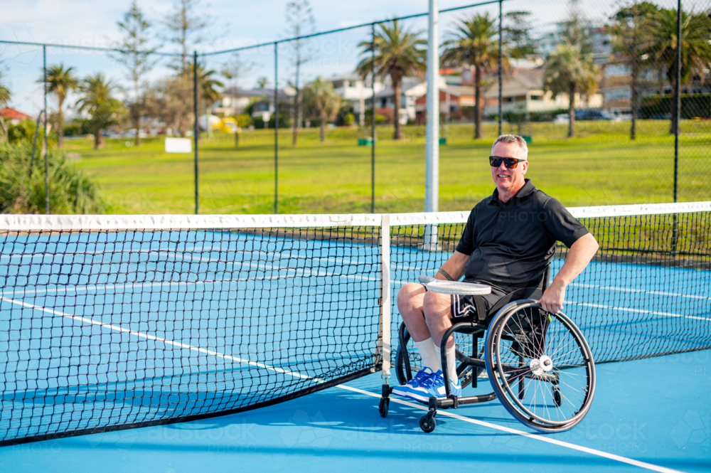 A man in a wheelchair is playing tennis on a hard court - Australian Stock Image