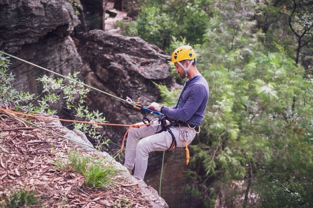 a man in full safety gear, abseiling down a cliff - Australian Stock Image