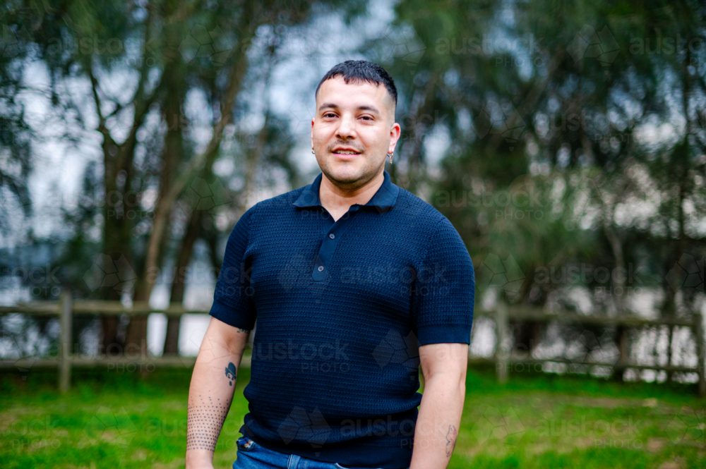 Image of A man in his 30s stands in a park during daylight, smiling in ...