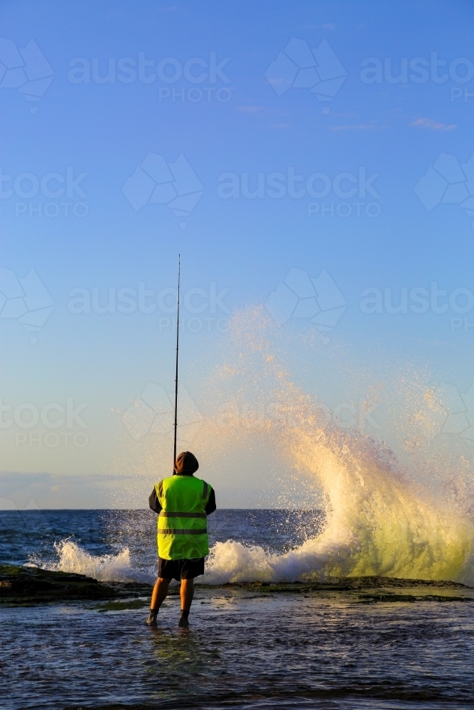 A man in his forties rock fishing at Wombarra Headland on the Illawarra Coast, NSW - Australian Stock Image
