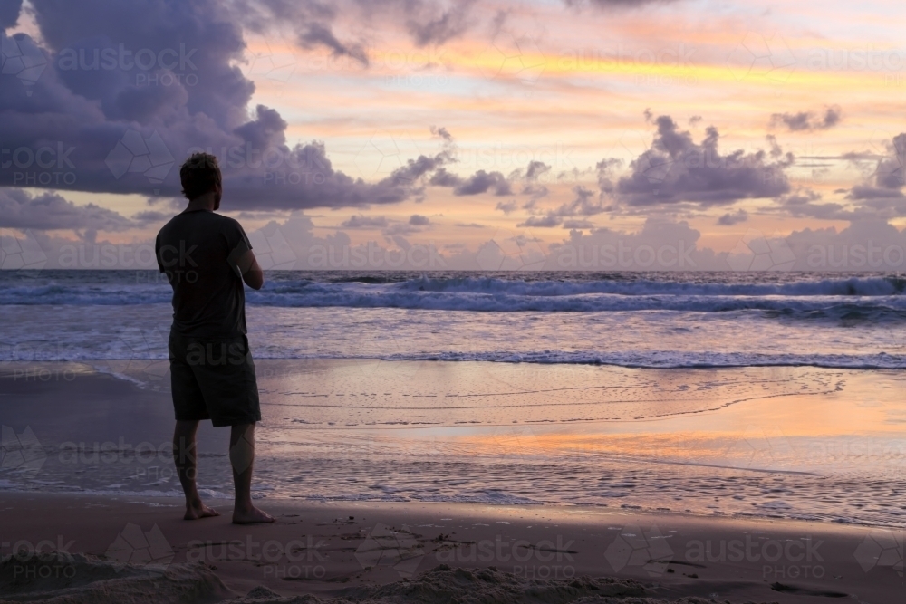 A man in his thirties contemplates the serenity of sunrise on K'gari Fraser Island, QLD. - Australian Stock Image