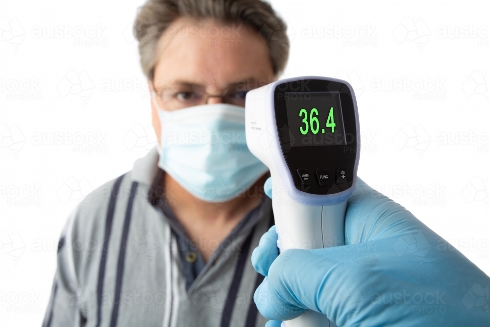 A man is temperature checked for fever or high temperature using  a non contact thermometer - Australian Stock Image