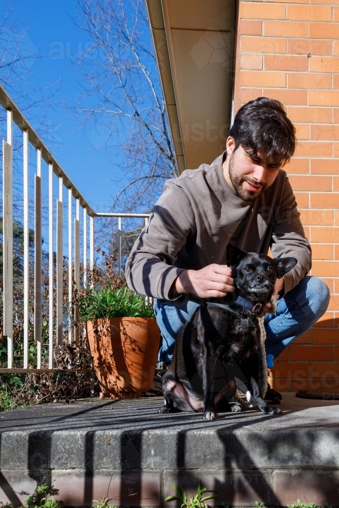 A man on his porch about to take his dog for a walk - Australian Stock Image