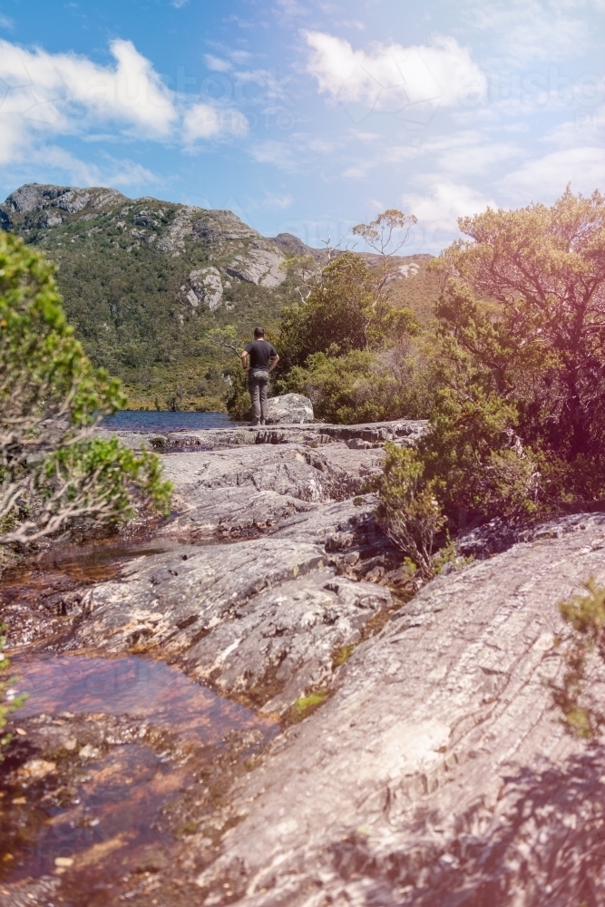 a man pauses at a viewpoint whilst hiking in Tasmania - Australian Stock Image