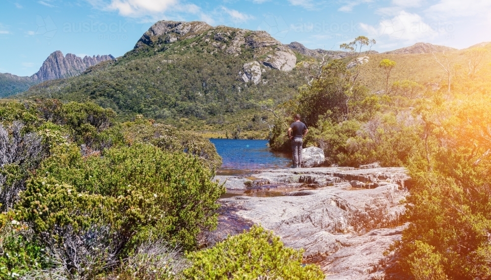 a man pauses at a viewpoint whilst hiking in Tasmania - Australian Stock Image