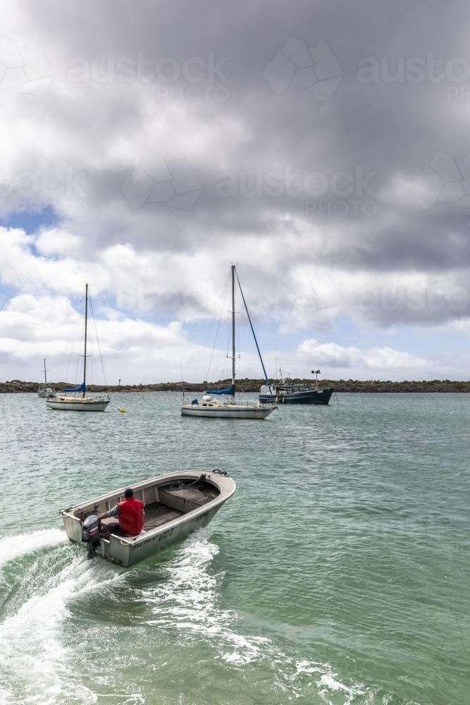 A man speeds away in a dingy at Grassy Harbour - Australian Stock Image