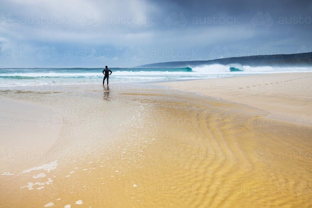 A man standing on a beach staring out to sea - Australian Stock Image