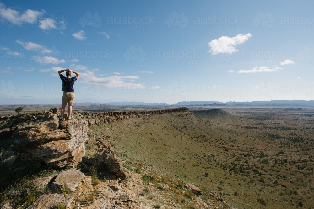 A man with hands on head overlooking the rugged landscape of the Flinders Ranges - Australian Stock Image