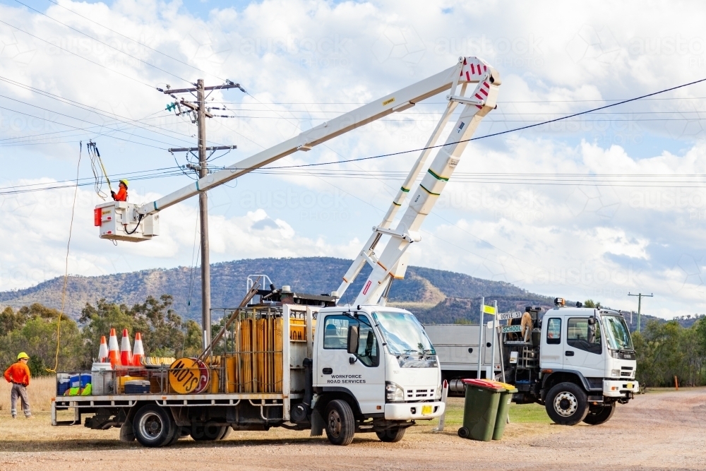 A man working on power lines from a cherry picker - Australian Stock Image