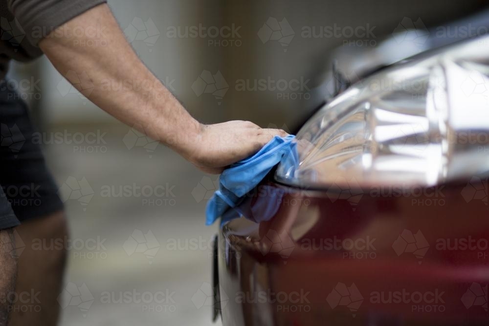 A mechanic cleans headlights on a car during a routine service. - Australian Stock Image