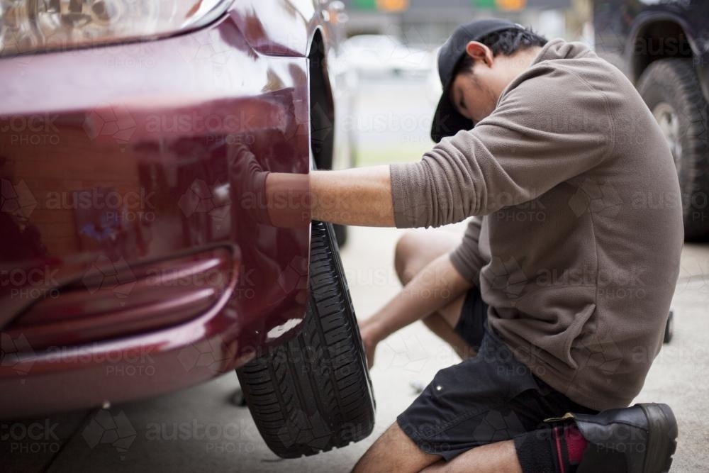 A mechanic inspects a tyre during a vehicle service. - Australian Stock Image