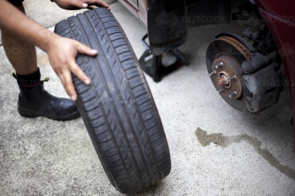 A mechanic inspects a tyre during a vehicle service. - Australian Stock Image