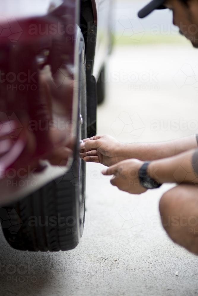 A mechanic inspects a tyre during a vehicle service. - Australian Stock Image