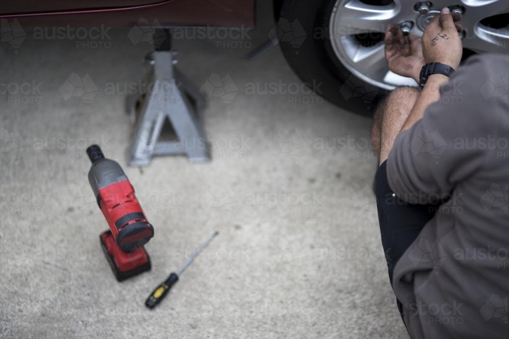 A mechanic inspects a tyre during a vehicle service. - Australian Stock Image