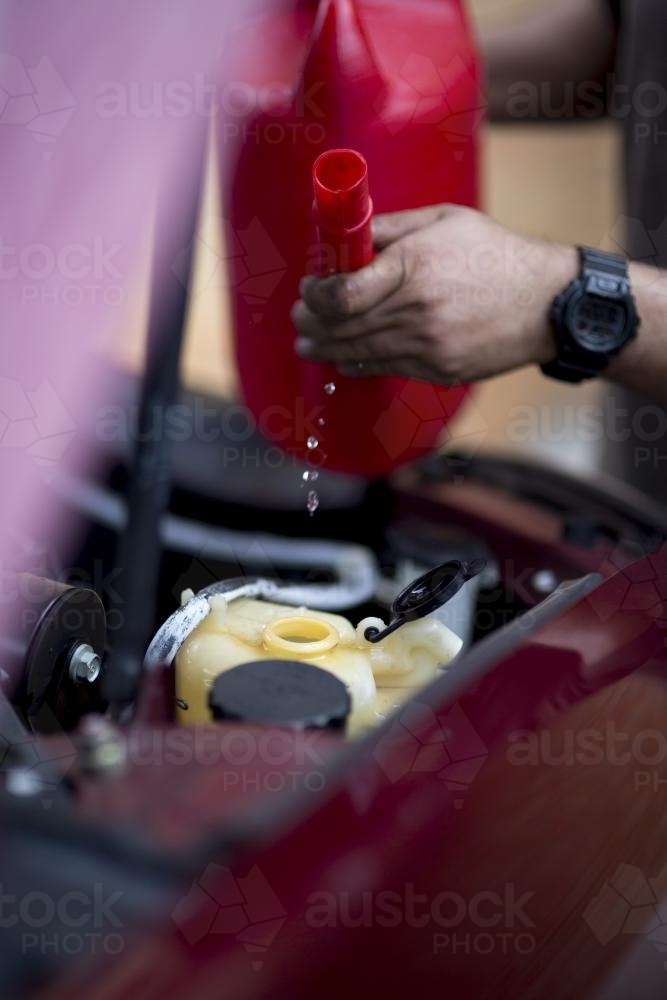 A mechanic refills windscreen washer fluid. - Australian Stock Image