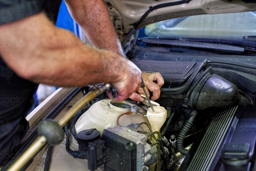 A mechanic servicing a luxury car in his workshop on the Gold Coast - Australian Stock Image
