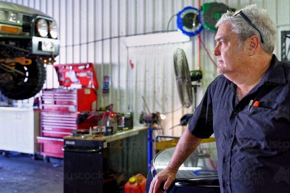 A mechanic standing in his workshop on the Gold Coast looking out - Australian Stock Image