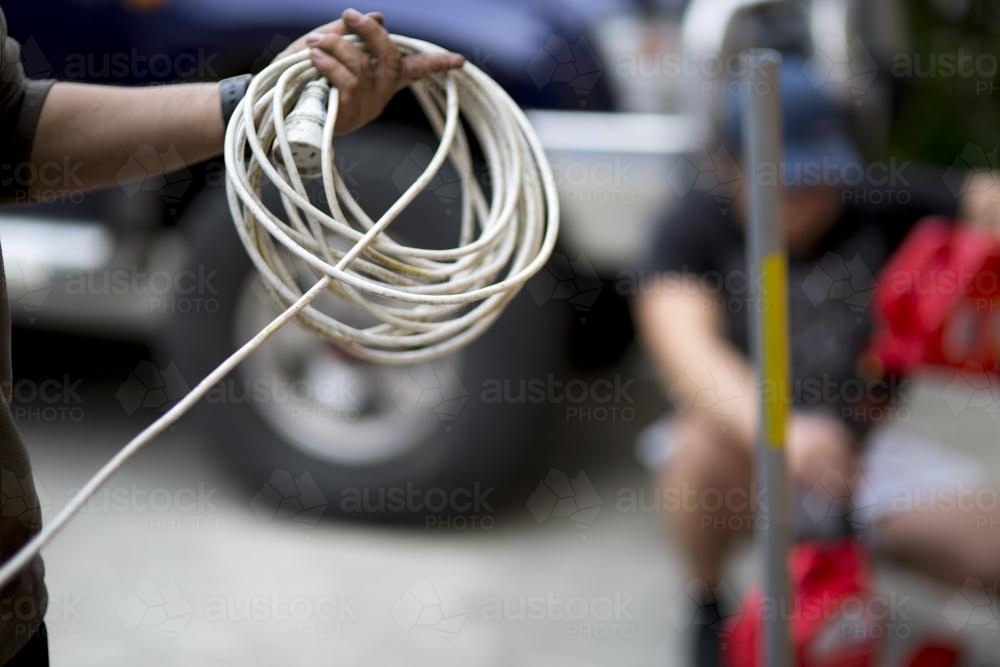 A mechanic winding an extension cord. - Australian Stock Image