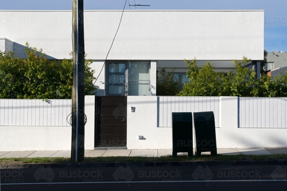 A modern, white house in the sun with two boxes on the nature strip - Australian Stock Image