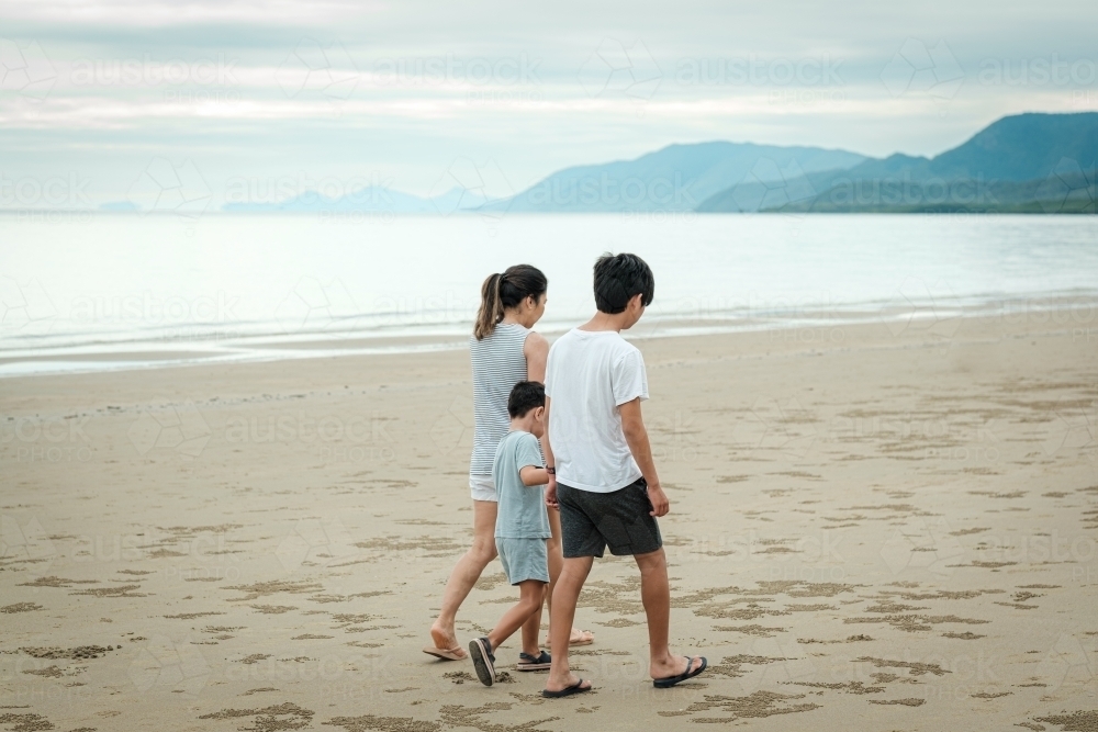 a mother and her kids walking along the beach - Australian Stock Image