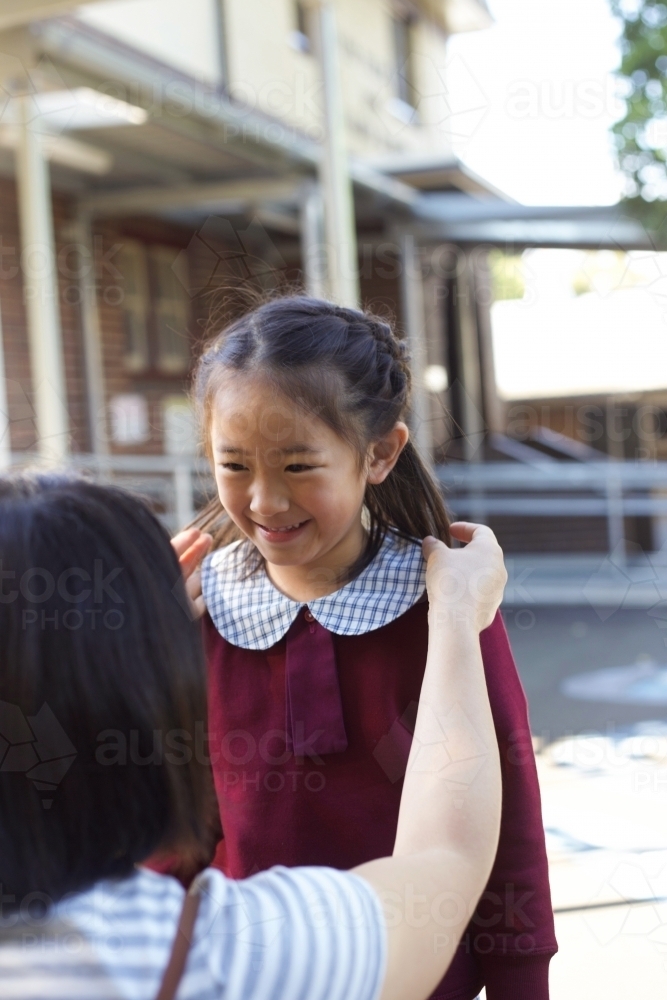 A mother fixing her daughter's hair at school - Australian Stock Image