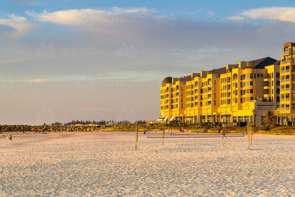 A multistory resort beside a white sandy beach with a volleyball court - Australian Stock Image