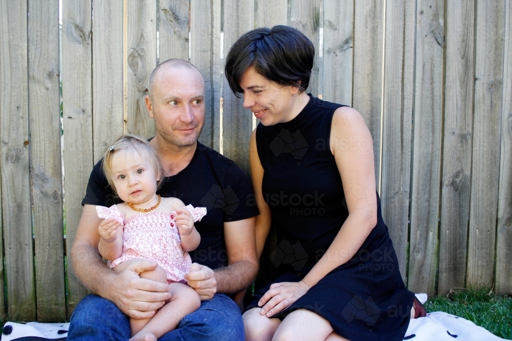 A mum and dad sitting on the grass with their baby girl - Australian Stock Image