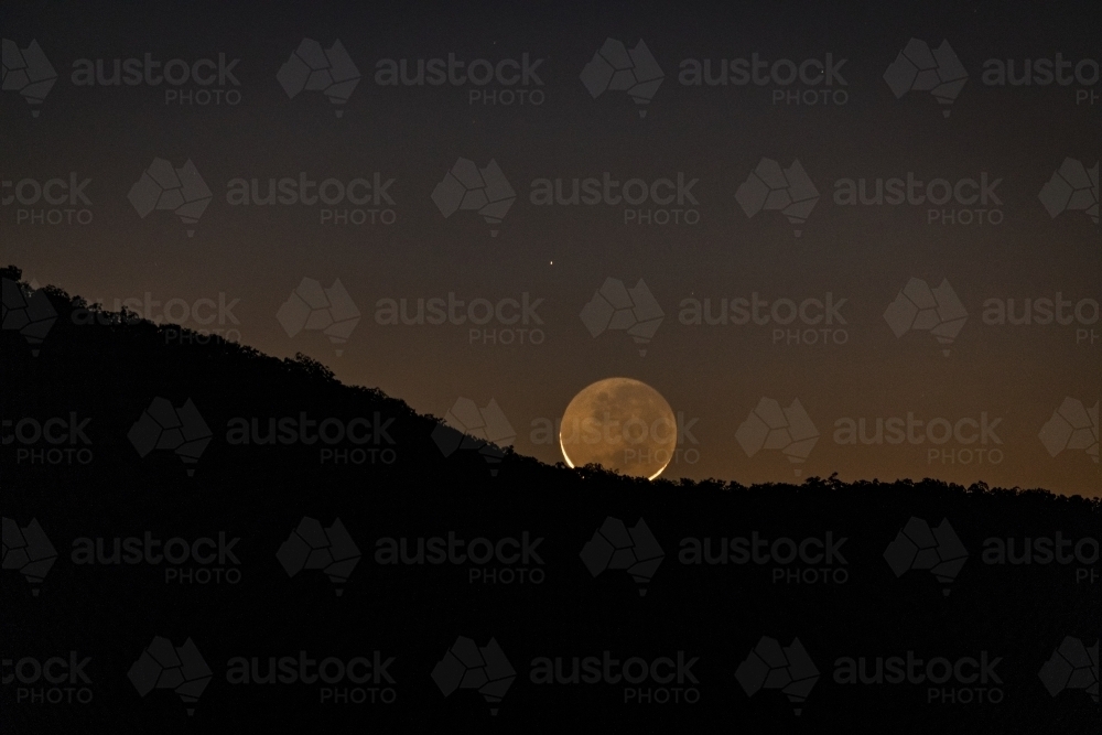 A new moon rising over a mountain ridge - Australian Stock Image