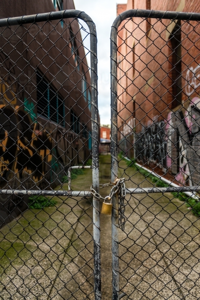 a padlocked gate at iconic grungy laneways of Melbourne city, with random graffiti - Australian Stock Image