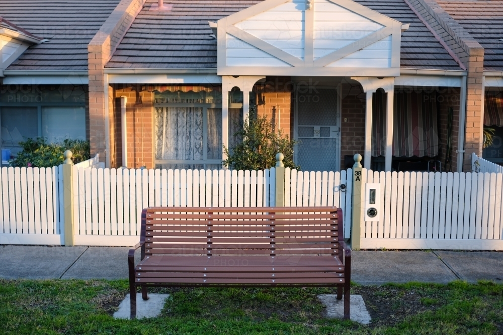 A park bench installed on the nature strip front of a row of houses - Australian Stock Image