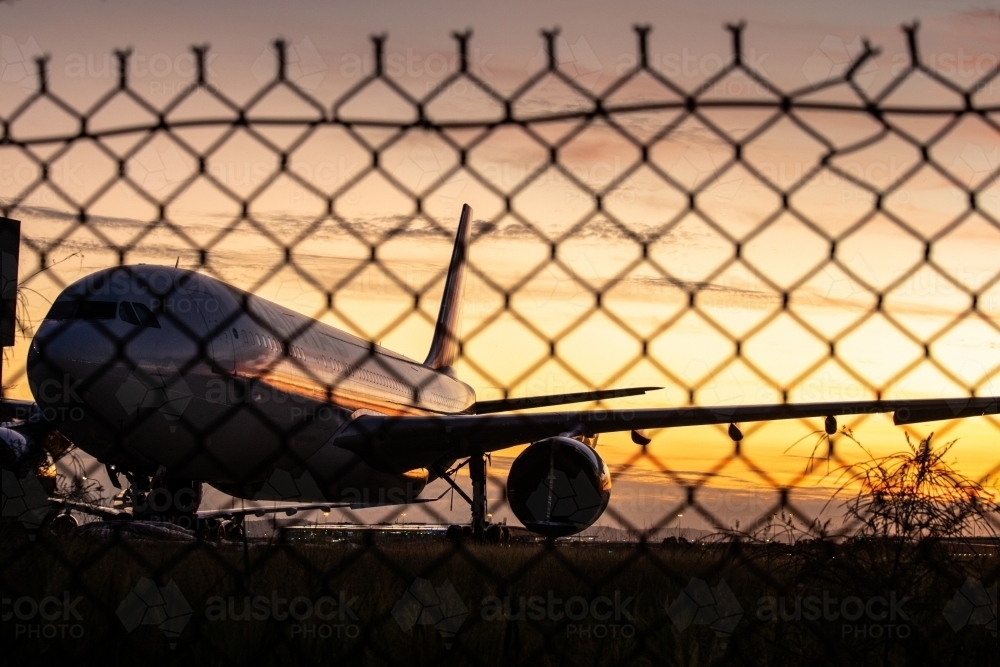 A parked plane behind a fence at the Brisbane domestic airport - Australian Stock Image
