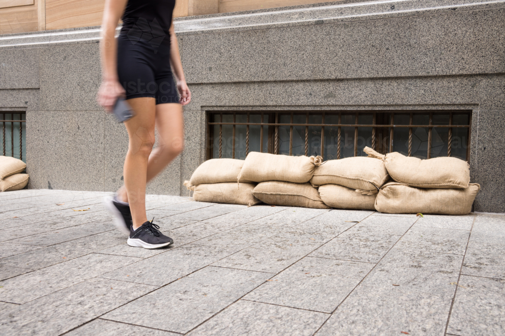 A pedestrian walks past sandbagged windows in the Brisbane CBD before a cyclone\ - Australian Stock Image
