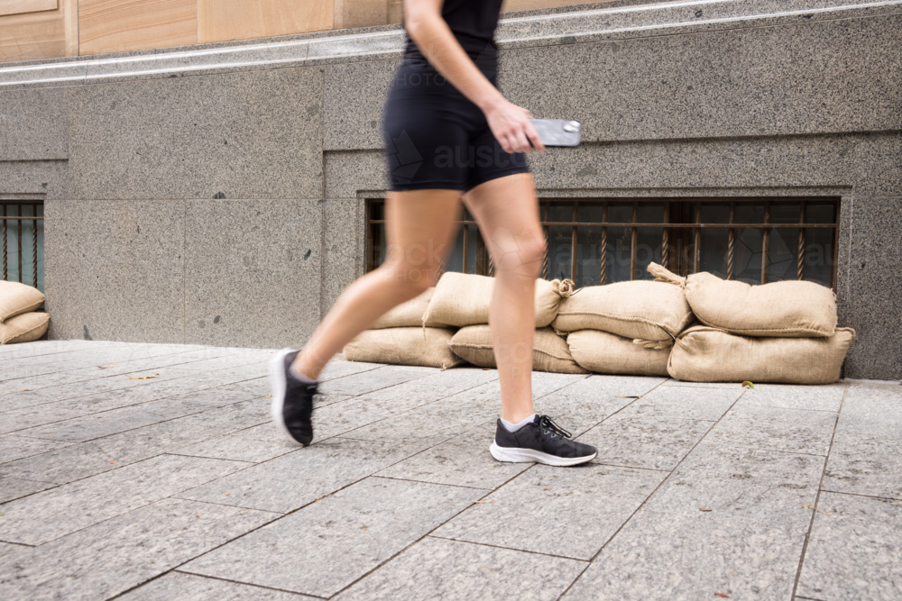 A pedestrian walks past sandbagged windows in the Brisbane CBD before a cyclone\ - Australian Stock Image