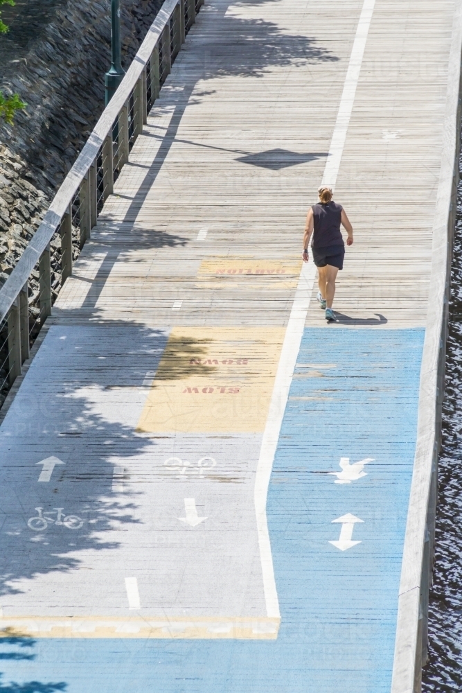 A person walking on a boardwalk with directional markings - Australian Stock Image