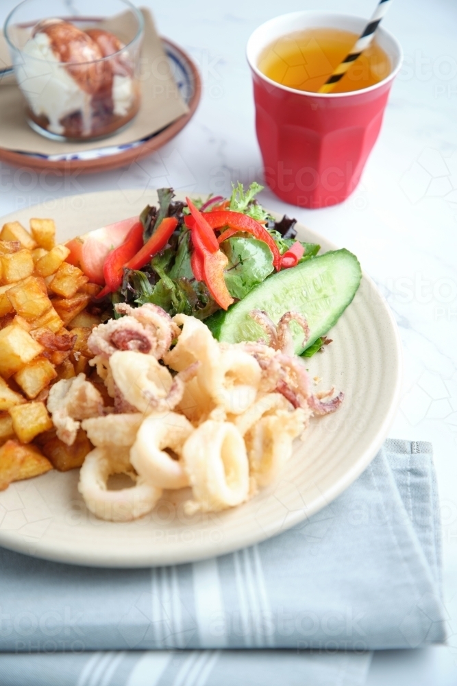 A plate of diced potatoes, salad and squid rings - Australian Stock Image