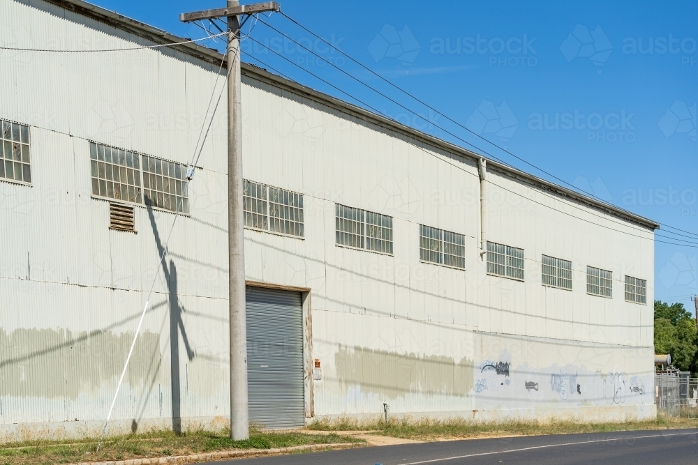 A power pole outside the door of a large corrugated iron warehouse - Australian Stock Image