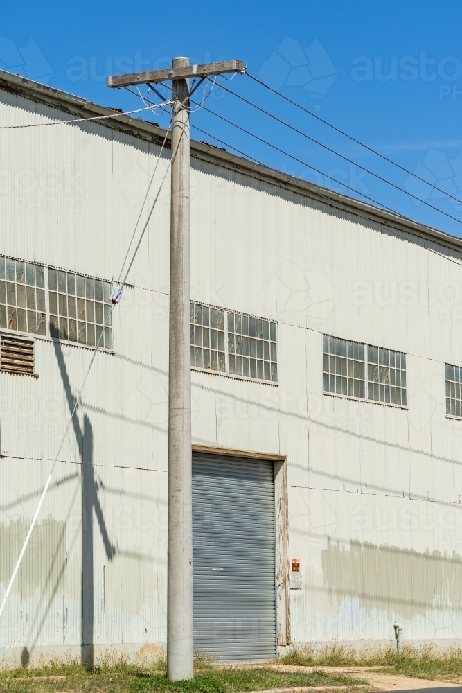 A power pole outside the door of a large corrugated iron warehouse - Australian Stock Image