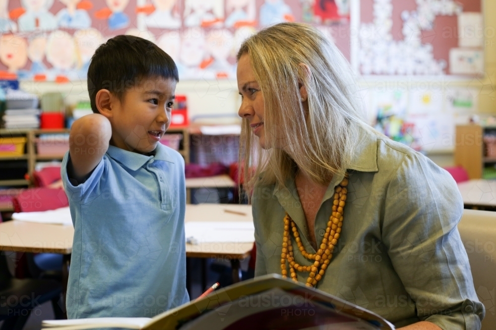 A primary school aged child speaking with his teacher - Australian Stock Image