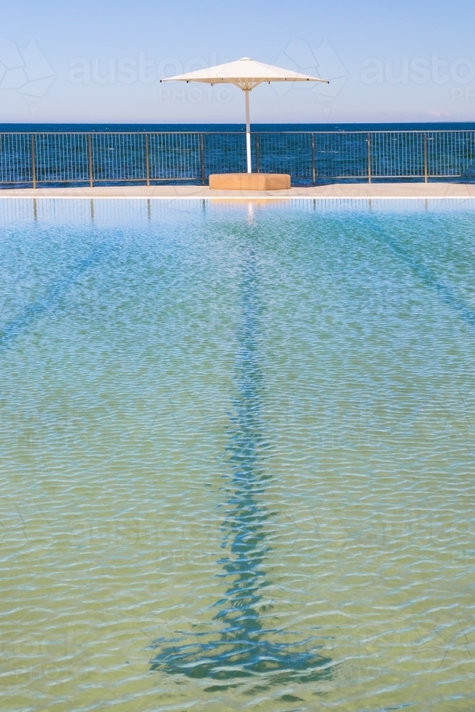 A public swimming pool with a sun umbrella on the edge - Australian Stock Image