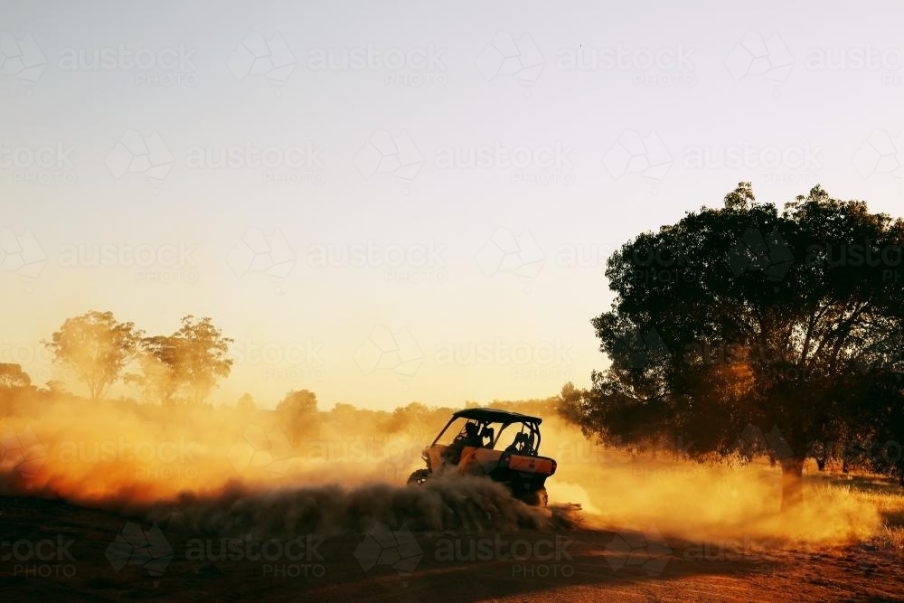 A quad bike doing a burnout in dust. - Australian Stock Image