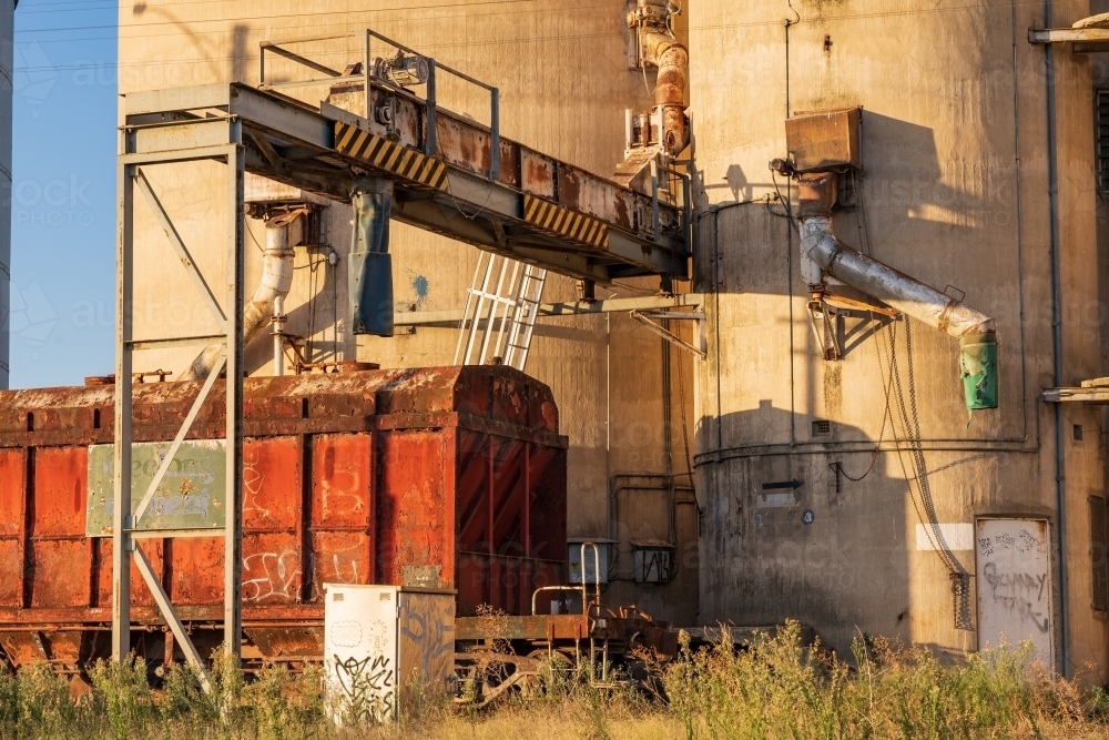 A railway grain carriage waiting alongside silos in a rural town - Australian Stock Image