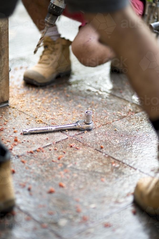 A ratchet and socket lies between two tradesmen on a home renovation site. - Australian Stock Image