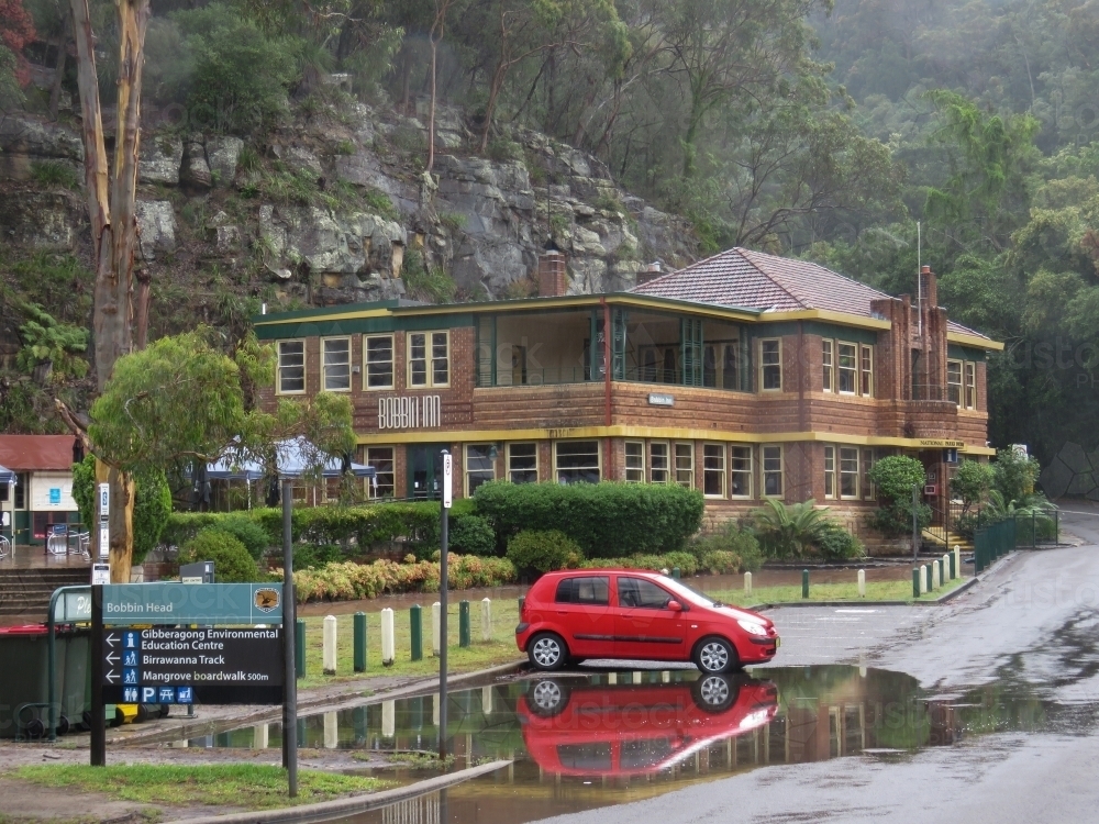 A red car sits in king-tidal water inundation on a misty morning - Australian Stock Image