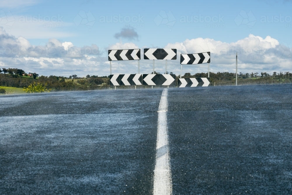 A road leading up to a directional sign at a T intersection - Australian Stock Image