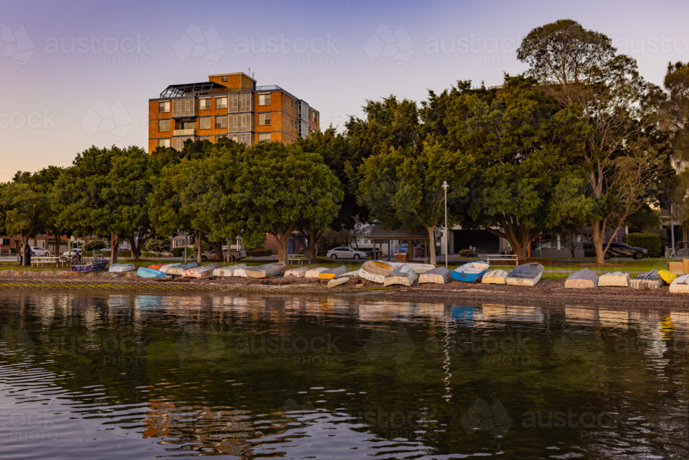 A row of multi-coloured dingies line the shoreline of Lake Macquarie - Australian Stock Image