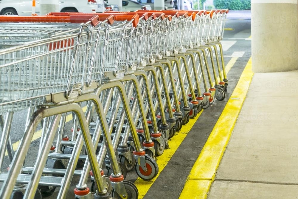A row of shopping trolleys next to the kerb in a carpark - Australian Stock Image