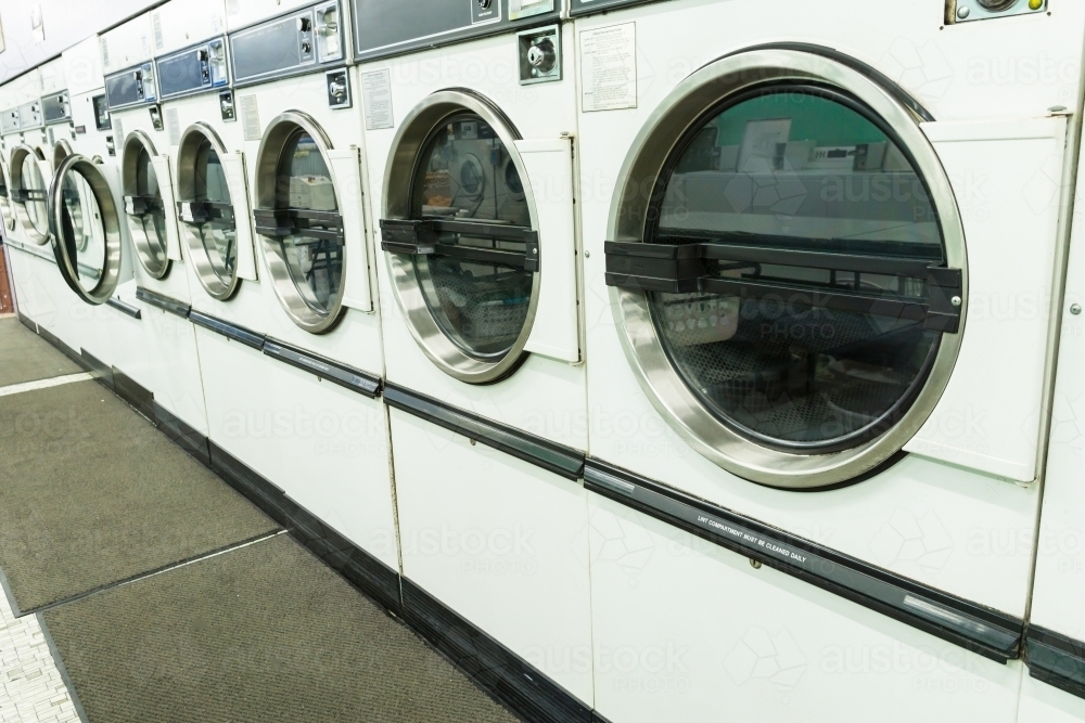 Image of A row of tumble dryers along a wall in a launderette