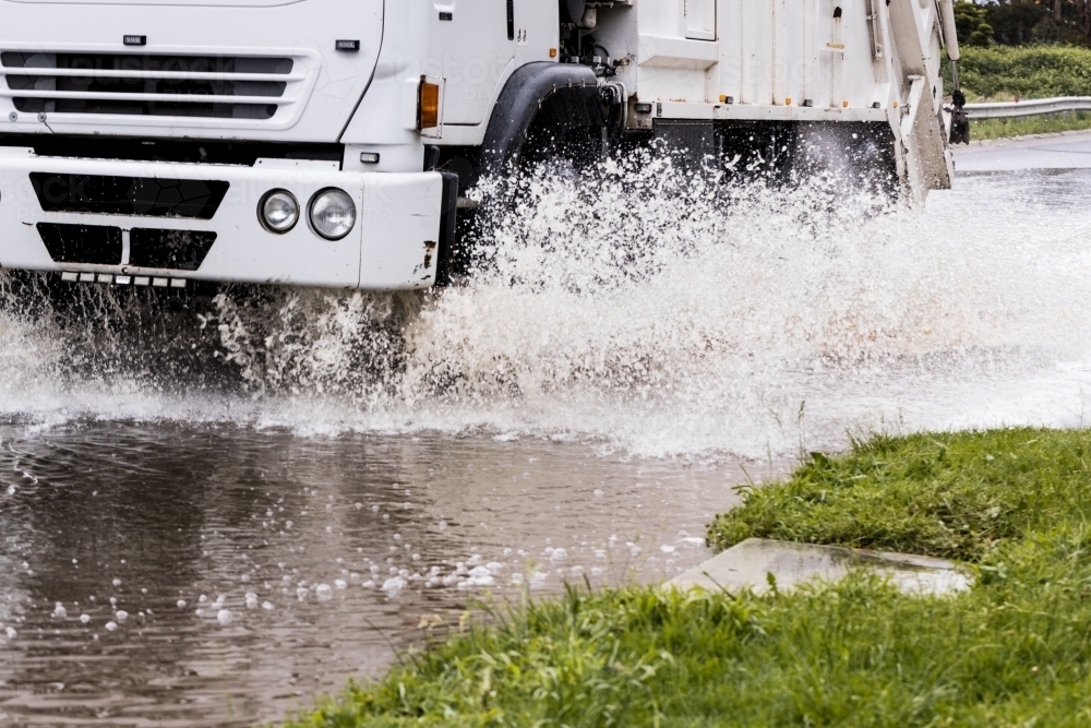A rubbish truck driving through flood water after a storm weather event - Australian Stock Image
