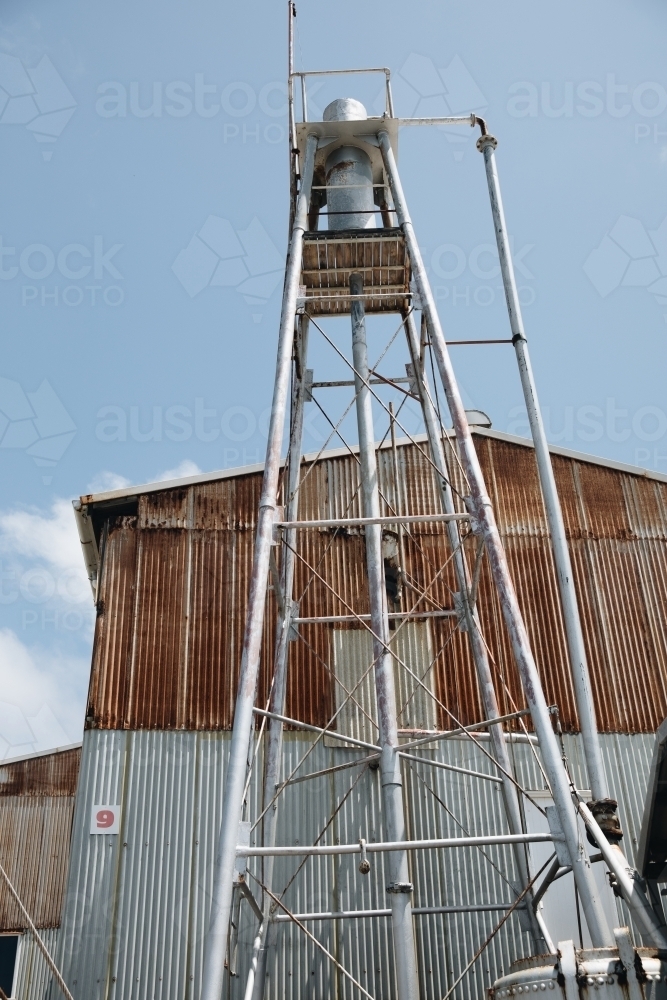 A rusted water tower with a building made of rusted corrugated metals in Old Whaling Station - Australian Stock Image