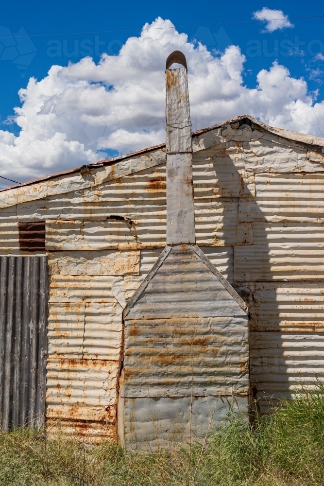 A rustic chimney up the side of a cottage all made from used corrugated iron - Australian Stock Image